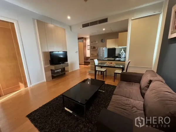 Condominium for rent in Chatuchak, Bangkok - Bright lounge with TV wall, dining table, and kitchenette featuring built-in cabinets and fridge.