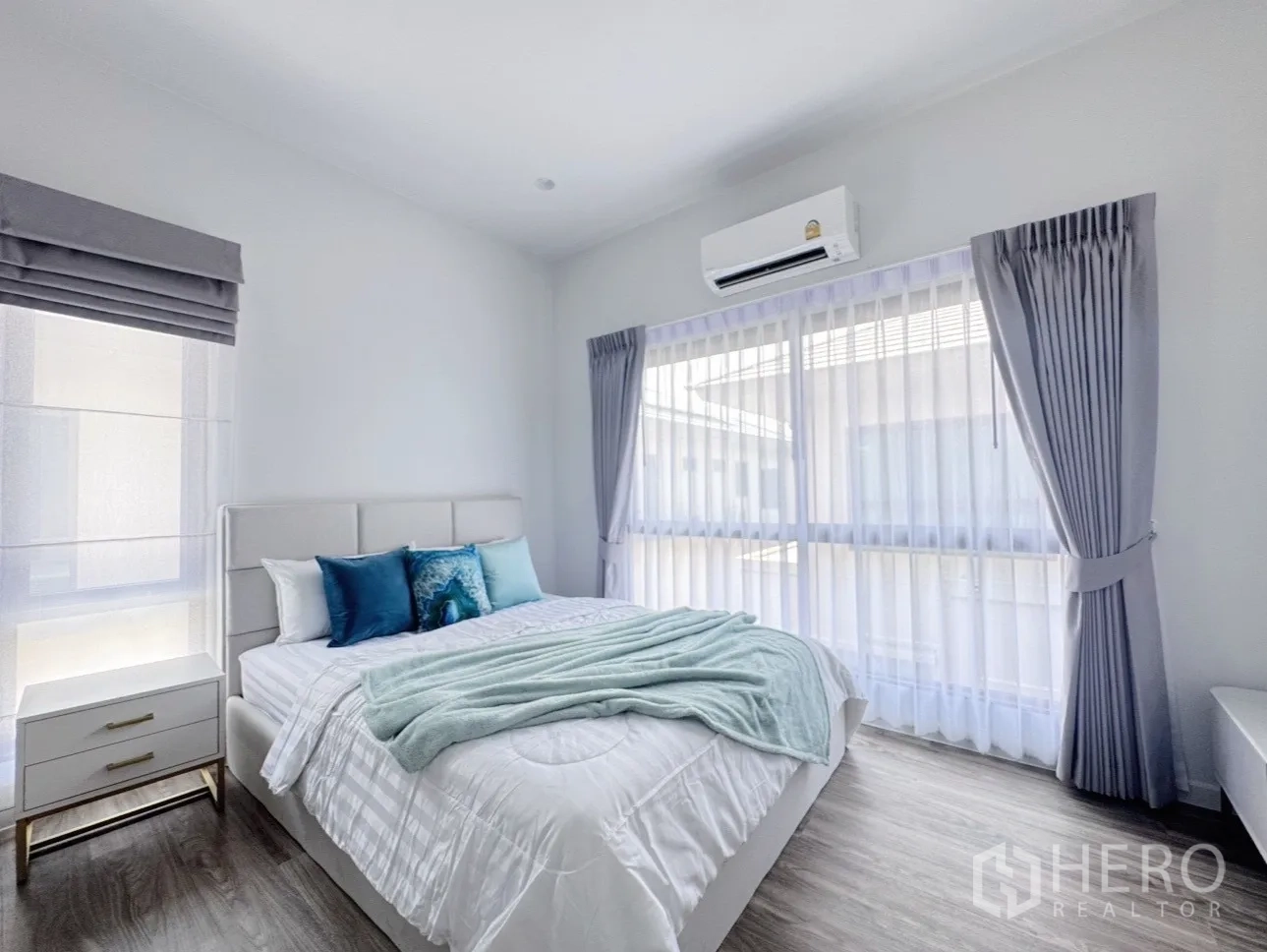 Detached House for rent or sale in Bang Kapi, Bangkok - Second bedroom with double bed, blue accent pillows and large corner windows.