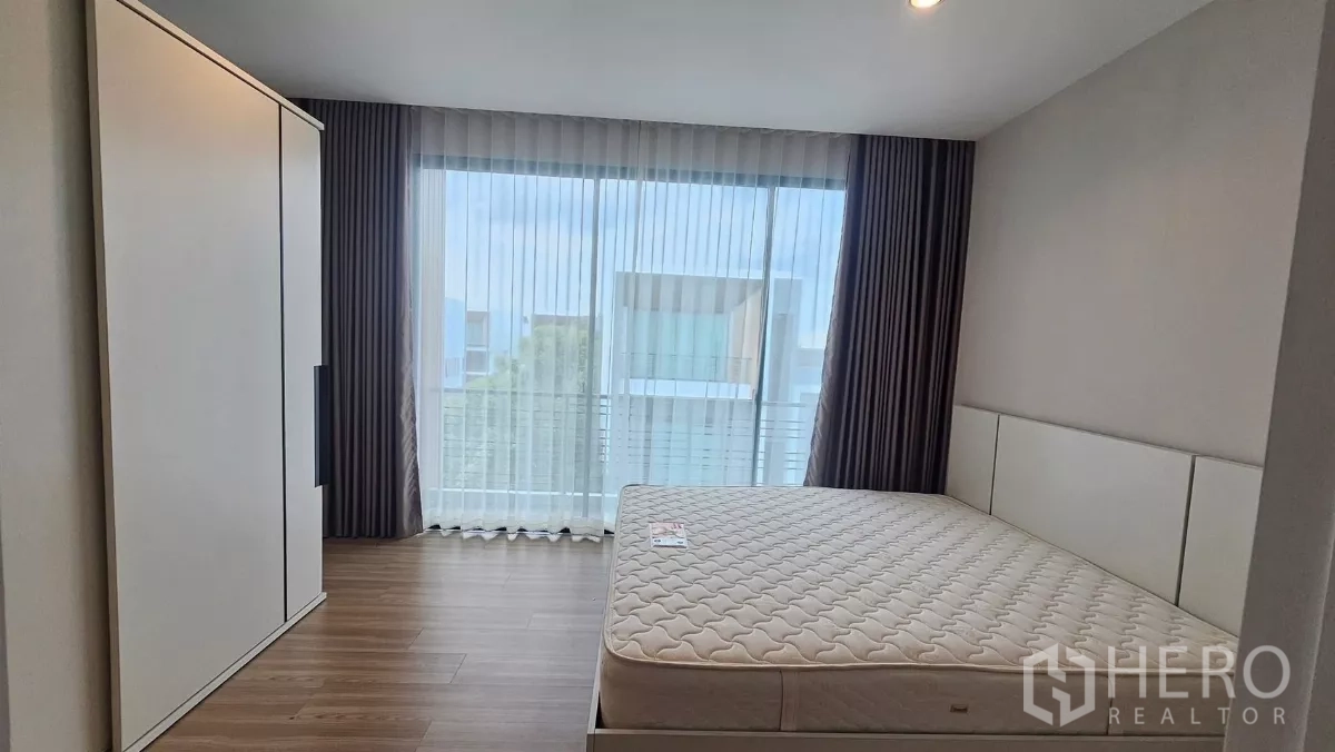 Townhouse for rent in Saphan Sung, Bangkok - Secondary bedroom with queen bed, wardrobe and floor-to-ceiling window.