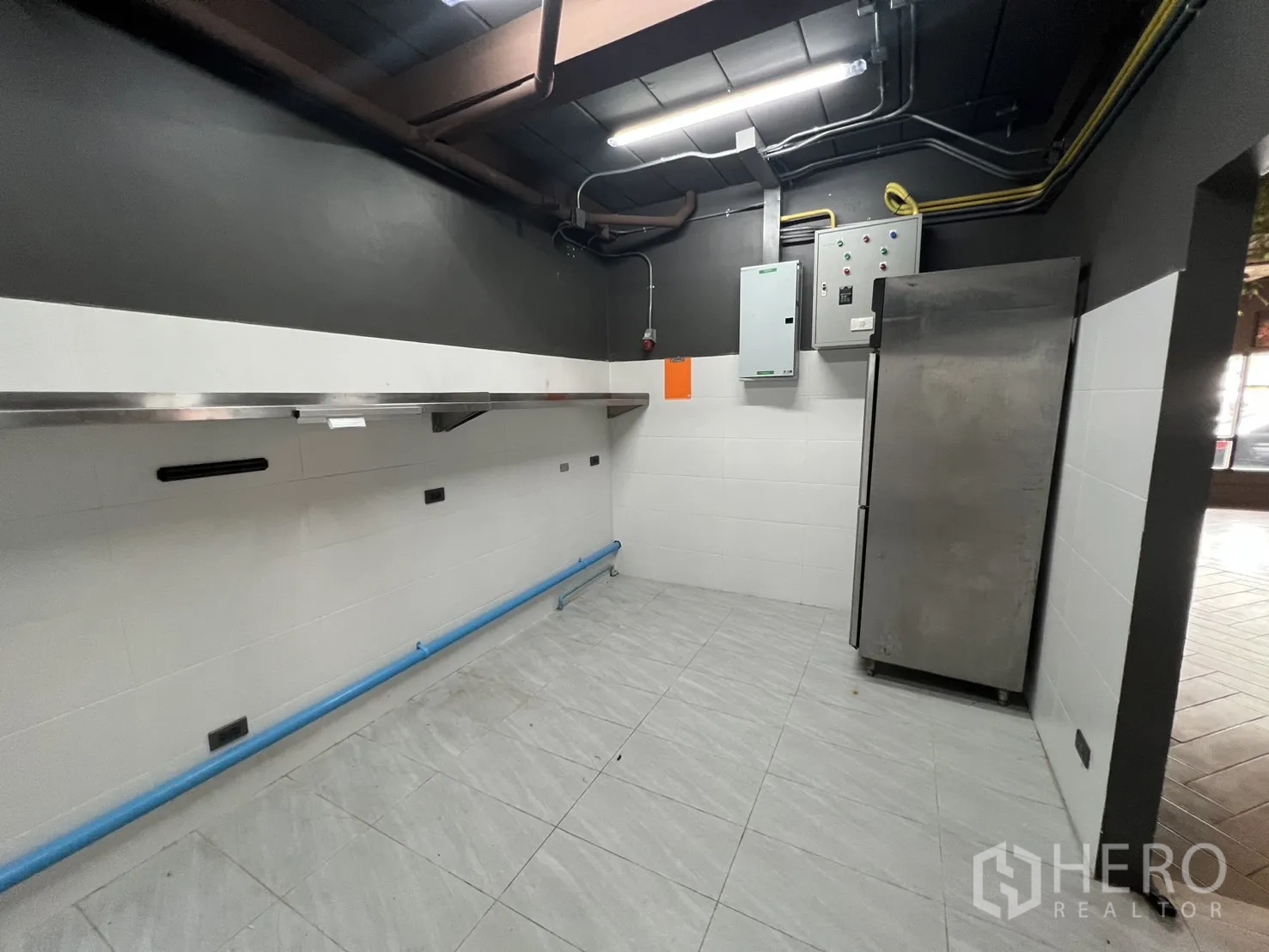 Retail Space for rent in Watthana, Bangkok - Prep area with electrical panels, bright lighting and a stainless commercial refrigerator.