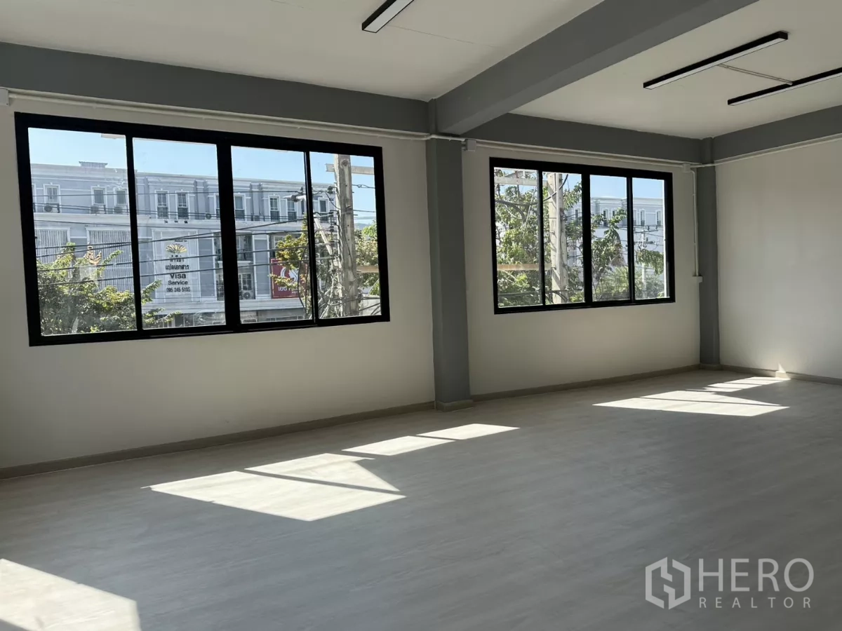 办公空间 出租在Phra Khanong, Bangkok - 明亮工作区，两扇大窗可见树影与周边建筑。