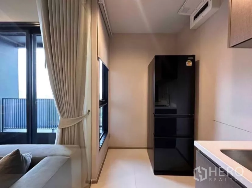 公寓 出租在Chatuchak, Bangkok - 厨房角落放置黑色冰箱，旁有窗户和阳台门