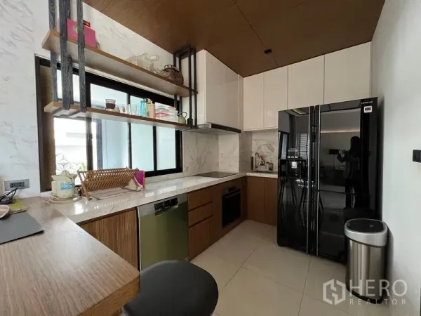 Townhouse for rent in Saphan Sung, Bangkok - Modern U-shaped kitchen with marble backsplash, black fridge, and open shelves by a window.