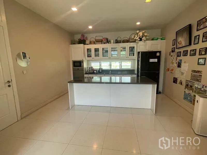 Detached House for rent in Bang Phli, Samut Prakan - Modern white kitchen with island, glass-front cabinets and built-in appliances.