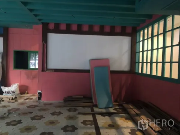 Retail Space for rent in Khlong Toei, Bangkok - Corner of shop interior with teal beams, white display panel and stacked boards against pink walls.