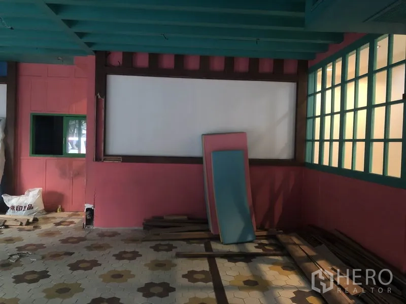 Retail Space for rent in Khlong Toei, Bangkok - Corner of shop interior with teal beams, white display panel and stacked boards against pink walls.