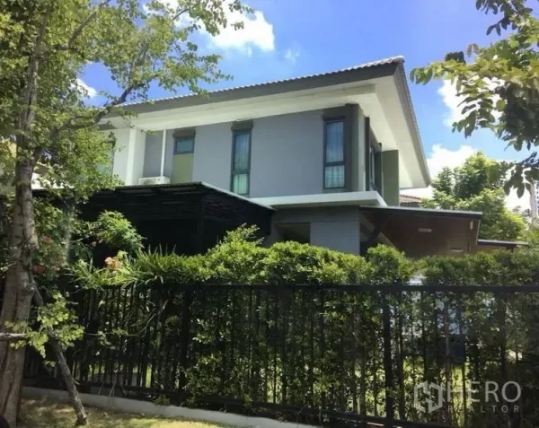 Detached House for sale - Modern two-storey detached house exterior behind black fence and lush hedges.