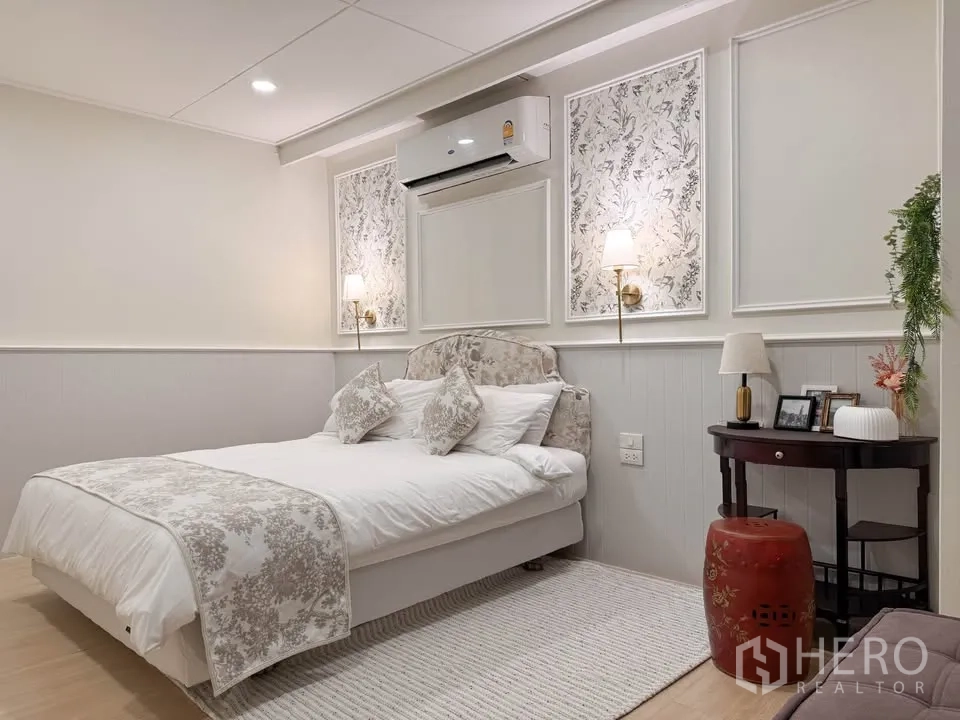 บ้าน ให้เช่าในHuai Khwang, Bangkok - ห้องนอนอบอุ่นเตียงบุผ้า โคมติดผนัง และโทนสีครีม.