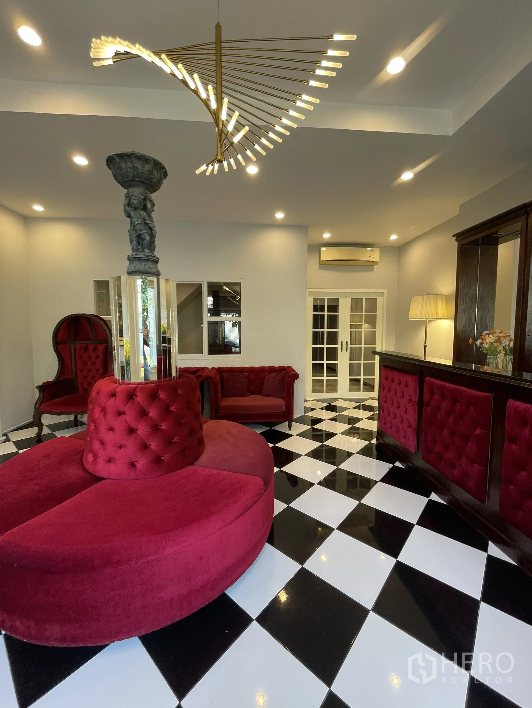 店屋 for rent in Bang Kapi, Bangkok - 接待休息区，螺旋造型吊灯、红色沙发与棋盘格地面。