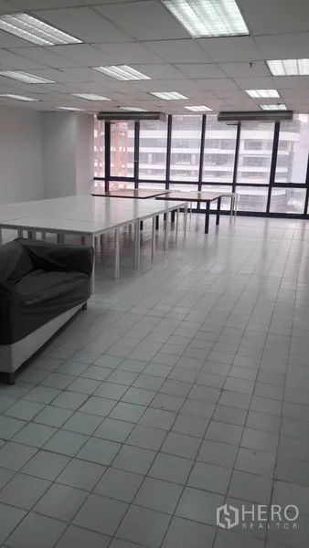 Office Space for rent in Huai Khwang, Bangkok - Bright workroom with tiled floors, long white tables, sofa and city-view windows.