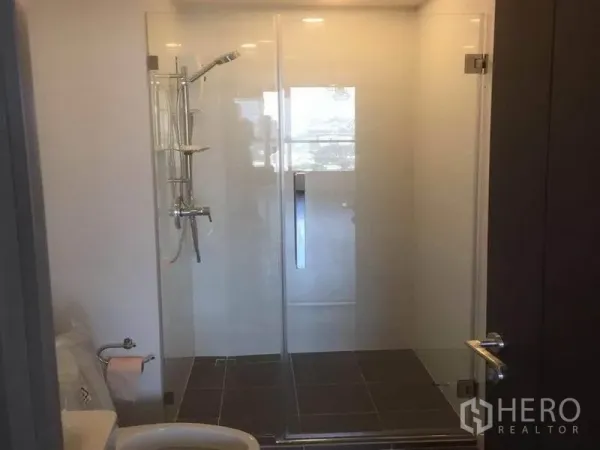 公寓 出售在Watthana, Bangkok - 现代浴室，配全玻璃淋浴间与洁白卫浴设施。