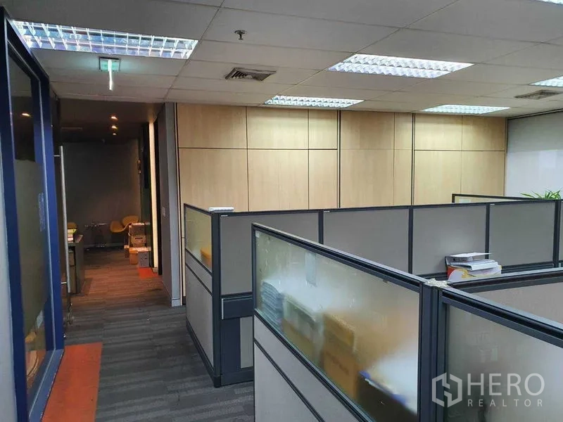 办公空间 出租在Watthana, Bangkok - 走廊通往工位区，木质墙面与网格天花灯。