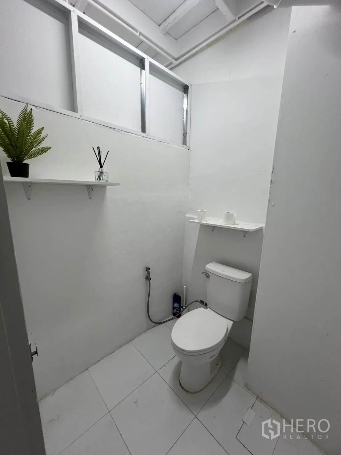 Shophouse for rent or sale in Khlong Toei, Bangkok - Clean restroom with toilet, shelf and decorative plant.