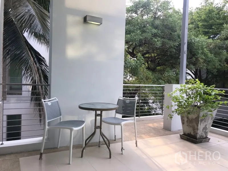 Townhouse for rent or sale in Chatuchak, Bangkok - Balcony with bistro table, two chairs and planter overlooking leafy greenery.