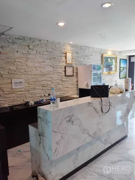 Shophouse for rent in Watthana, Bangkok - Marble reception counter with stone accent wall and framed artwork.