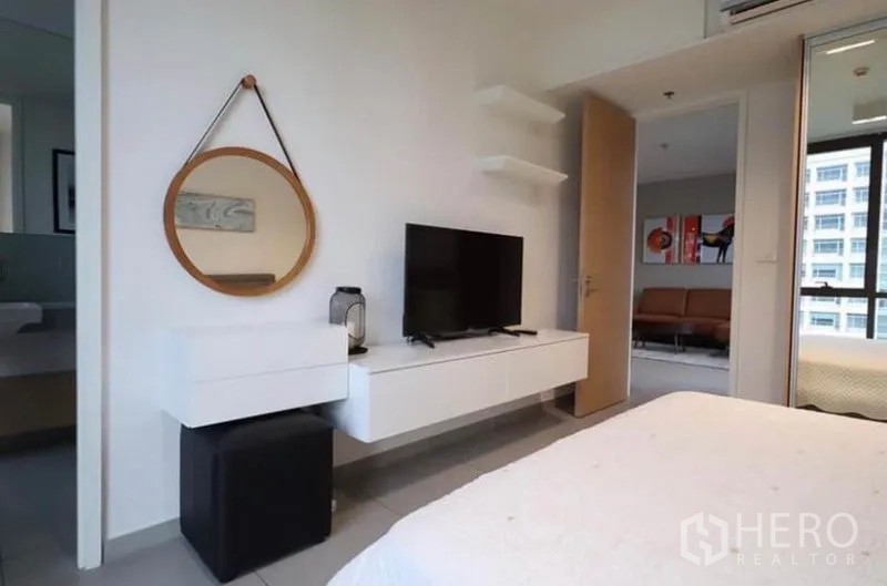 公寓 出租在Watthana, Bangkok - 主卧一角，壁挂柜、圆形镜与电视。