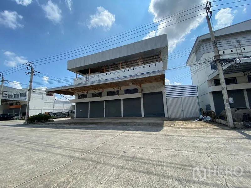 คลังสินค้า ให้เช่าหรือขายในBang Phli, Samut Prakan - ภาพด้านข้างอาคารโกดังทันสมัย มีชายคาคลุมจุดขนถ่ายสินค้าและถนนหน้าโครงการกว้าง