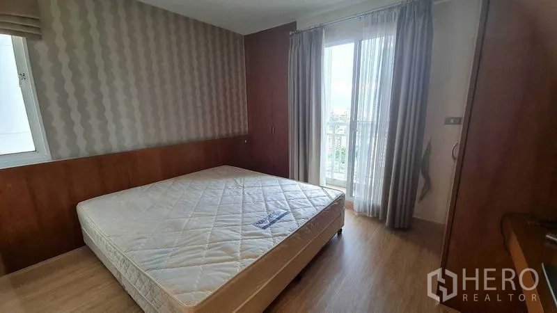 公寓 出租或出售在Watthana, Bangkok - 主卧带大窗与阳台出入口，木饰面与双人床。