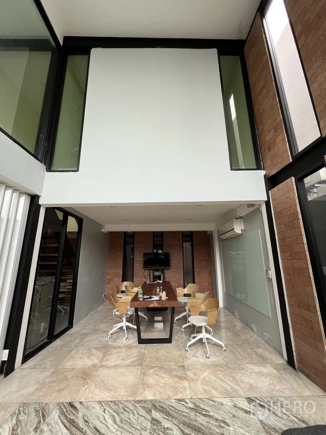 Detached House for rent or sale in Phra Khanong, Bangkok - Dining or meeting area under mezzanine with long wooden table and modern chairs.