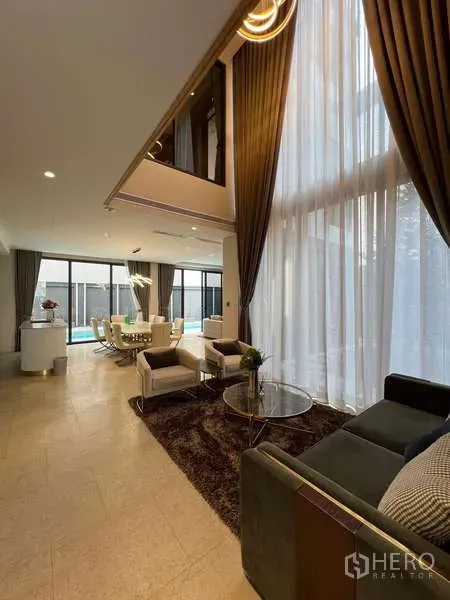 Detached House for rent in Suan Luang, Bangkok - Double‑height living area with tall curtains and view toward the dining zone.
