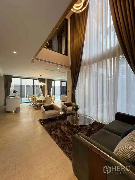 Detached House for rent in Suan Luang, Bangkok - Double‑height living area with tall curtains and view toward the dining zone.