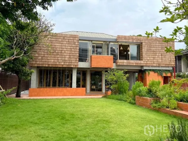 Retail Space for rent in Watthana, Bangkok - Contemporary two‑storey commercial building with shingle cladding and a landscaped lawn in a green community setting.