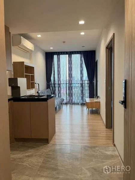 公寓 出售在Watthana, Bangkok - 开放式起居区与一体化小厨房，木地板，大落地门通向阳台的现代公寓。