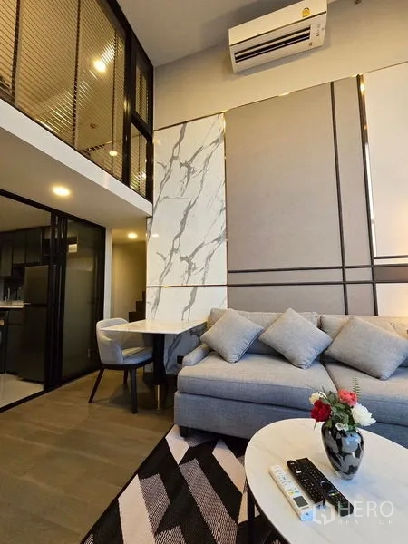 Condominium for rent - Living room with sofa, marble accent wall, dining nook, and high ceiling.