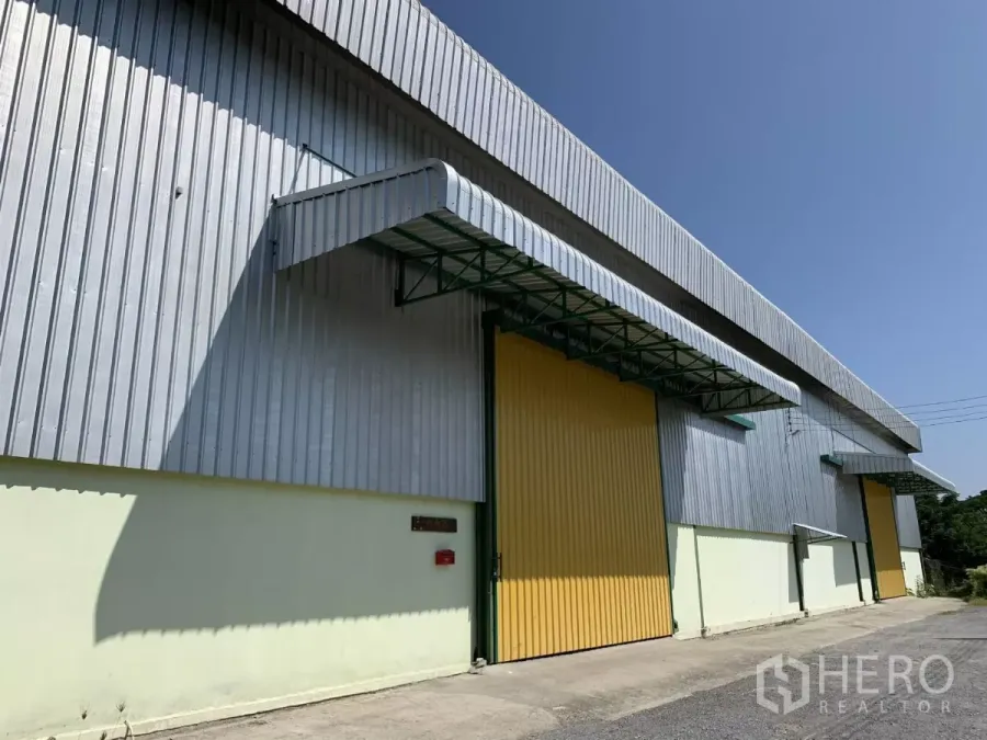 Warehouse for rent in Lat Krabang, Bangkok - Metal-clad warehouse facade in Lat Krabang with a yellow sliding door and covered loading awning.