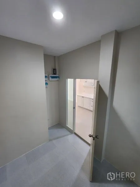 联排别墅 出租在Wang Thonglang, Bangkok - 灰色墙面的小玄关，嵌灯，门通向明亮的厨房区。