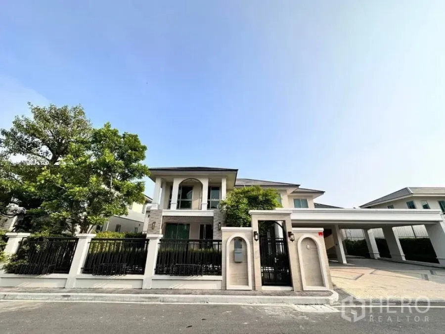 独立式住宅 出租或出售在Lat Krabang, Bangkok - 现代两层独栋住宅外观，带围栏与车棚，门前绿树。