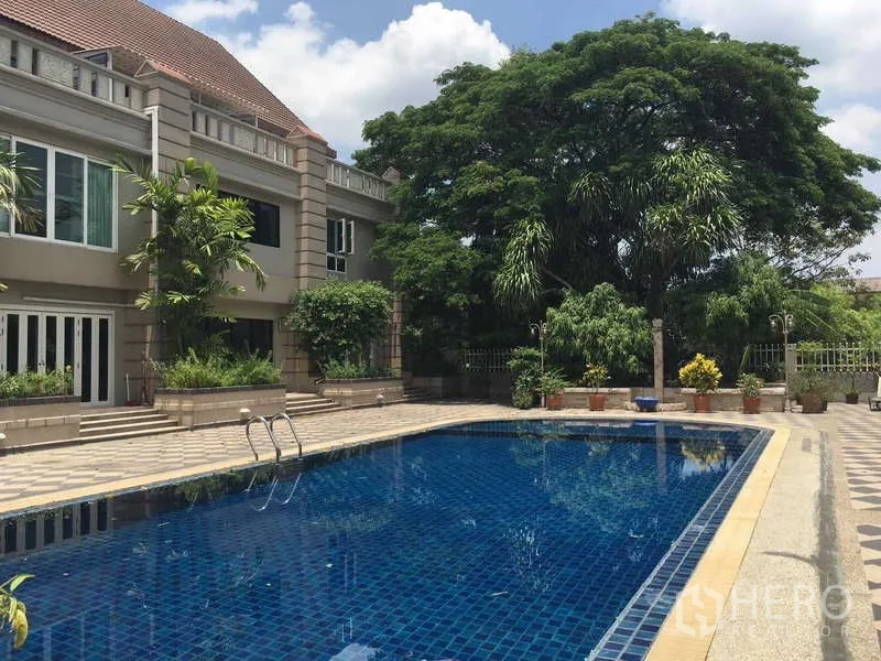 联排别墅 出租在Khlong Toei, Bangkok - 低层住宅旁的公用游泳池，周围绿树成荫