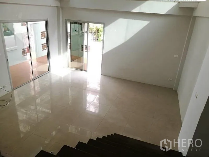 Detached House for rent in Phra Khanong, Bangkok - View from the staircase onto a bright living space with large sliding glass doors.