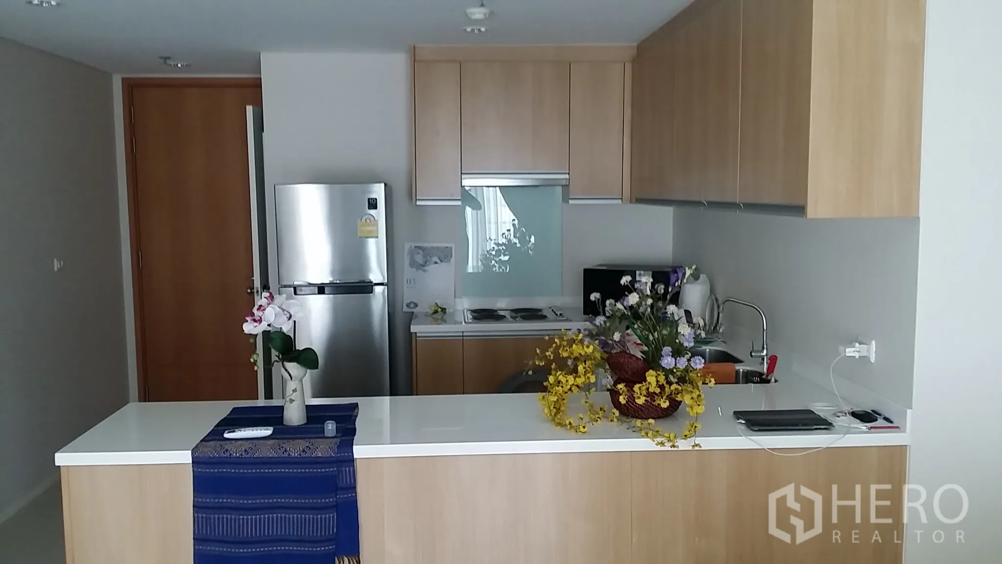 公寓 出租或出售在Ratchathewi, Bangkok - 开放式厨房，带中岛、浅木橱柜、电炉、水槽与不锈钢冰箱。