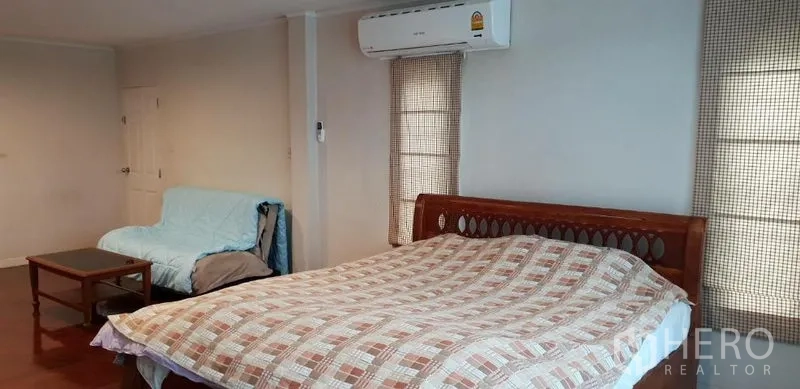 独立式住宅 出租在Phra Khanong, Bangkok - 宽敞卧室，木质床与格纹被套，壁挂空调，沙发与小茶几，窗帘遮光。