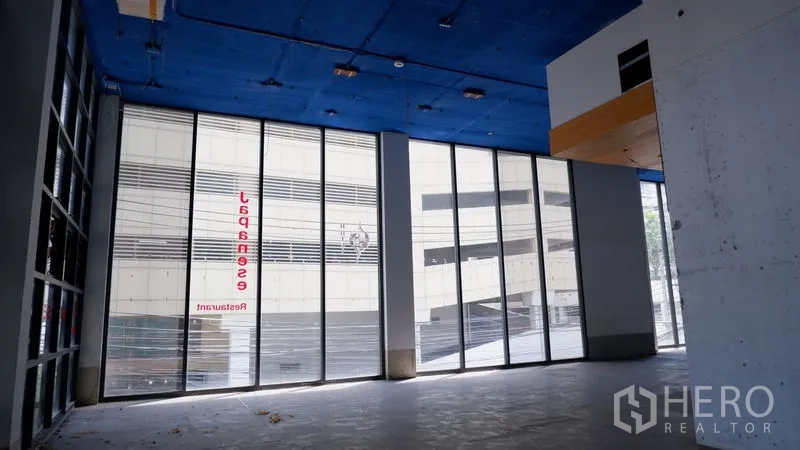 Retail Space for rent in Watthana, Bangkok - Corner retail frontage with tall glass panels and high ceiling facing the street.