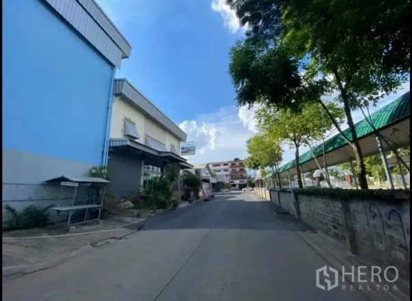 คลังสินค้า ให้เช่าในSai Mai, Bangkok - ด้านหน้าโกดังติดถนนภายใน ใกล้ทางเดินมีหลังคาและอาคารพักอาศัยเตี้ย ๆ