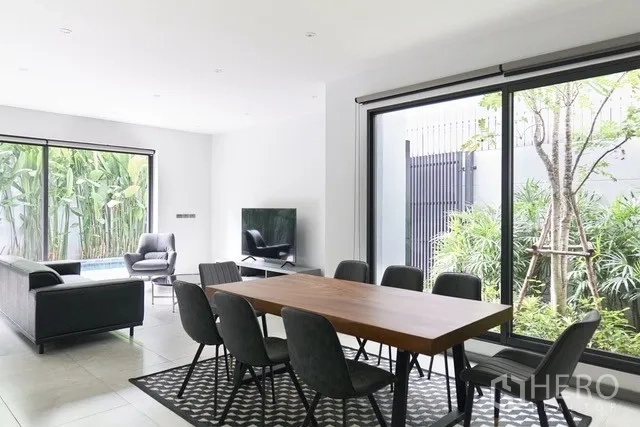 Townhouse for sale in Watthana, Bangkok - Dining room with floor-to-ceiling windows overlooking landscaped greenery.