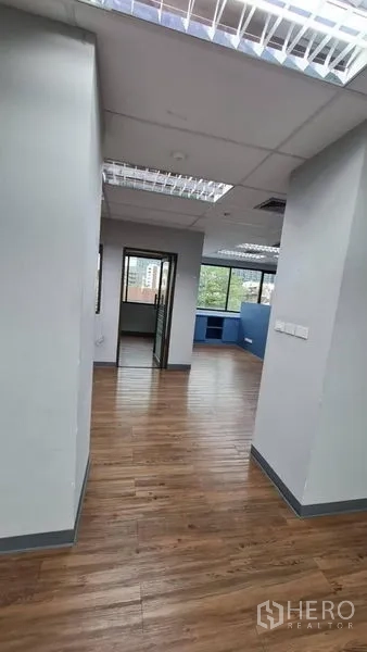 办公空间 出租在Watthana, Bangkok - 开放式布局，格栅灯、蓝色储物墙与多面窗。