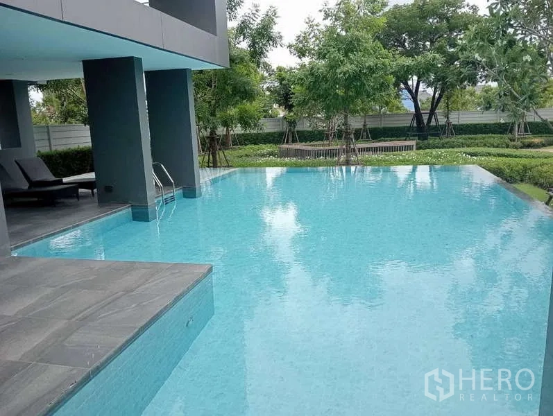 Detached House for rent in Bang Phli, Samut Prakan - Residents’ swimming pool beside a garden with lounge chairs and shaded terrace.