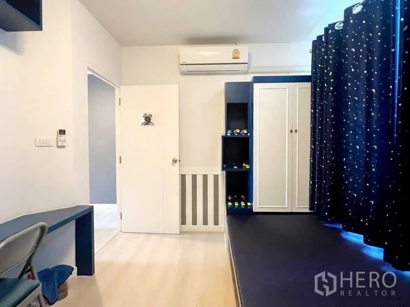 Detached House for rent in Bang Phli, Samut Prakan - Second bedroom with platform bed, blue built-ins, wardrobe and air conditioner.