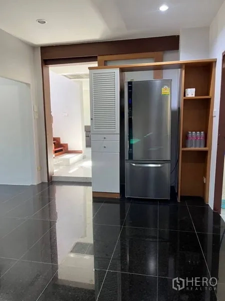 Detached House for rent in Samut Prakan - Kitchen zone with tall refrigerator nook and glossy black floor tiles.