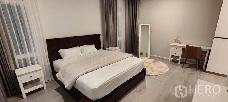 Detached House for rent in Prawet, Bangkok - Spacious second bedroom with double bed, work desk, and floor-to-ceiling curtains.