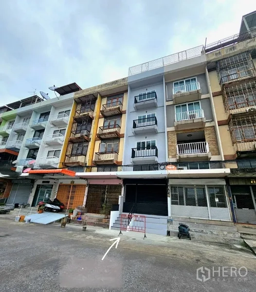 อาคารพาณิชย์ ให้เช่า - ด้านหน้าตึกแถวรีโนเวทพร้อมประตูม้วนและระเบียงในย่านบางนา