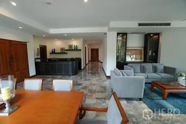 Apartment for rent in Watthana, Bangkok - Dining area beside a long hallway with a built-in bar and recessed lighting in a spacious living zone.
