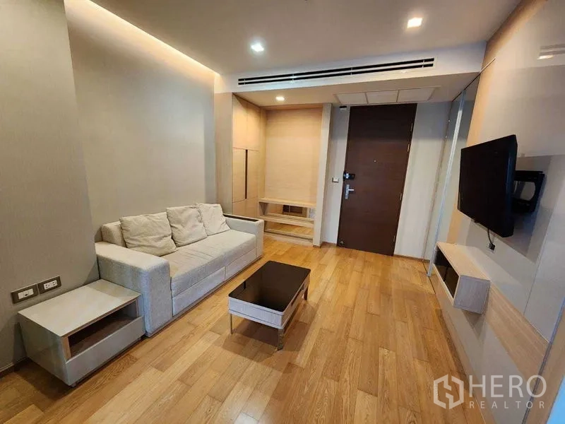 公寓 出售在Ratchathewi, Bangkok - 入户旁的客厅，米色沙发、电视柜与浅色木地板，简洁现代。