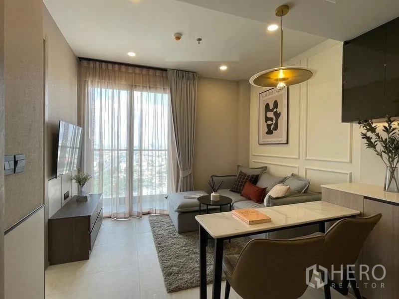 คอนโด ให้เช่าในPathum Wan, Bangkok - ห้องนั่งเล่นหน้าต่างสูงแบบระเบียง โซฟาเข้ามุม และทีวีตรงข้าม