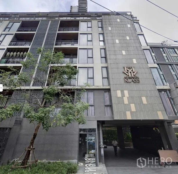 公寓 出售在Pathum Wan, Bangkok - 中高层公寓外立面，KLASS 标识与绿化入口。