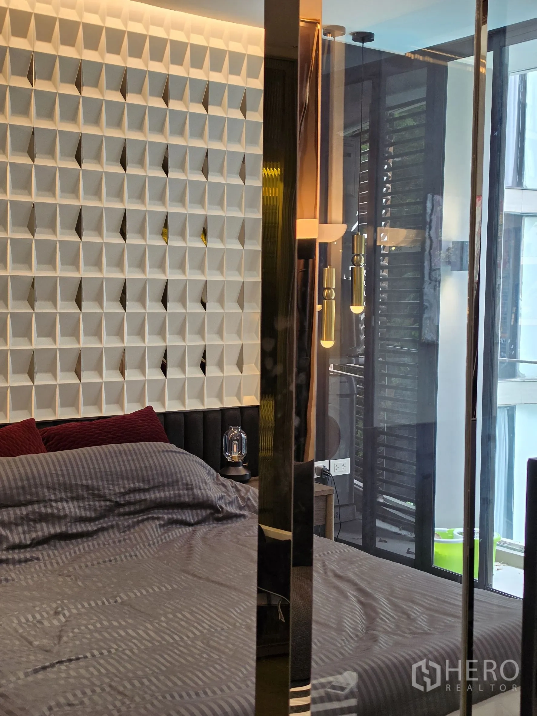 Condominium for rent in Khlong Toei, Bangkok - Bedroom with geometric feature wall, pendant lights, and glass door to the balcony.