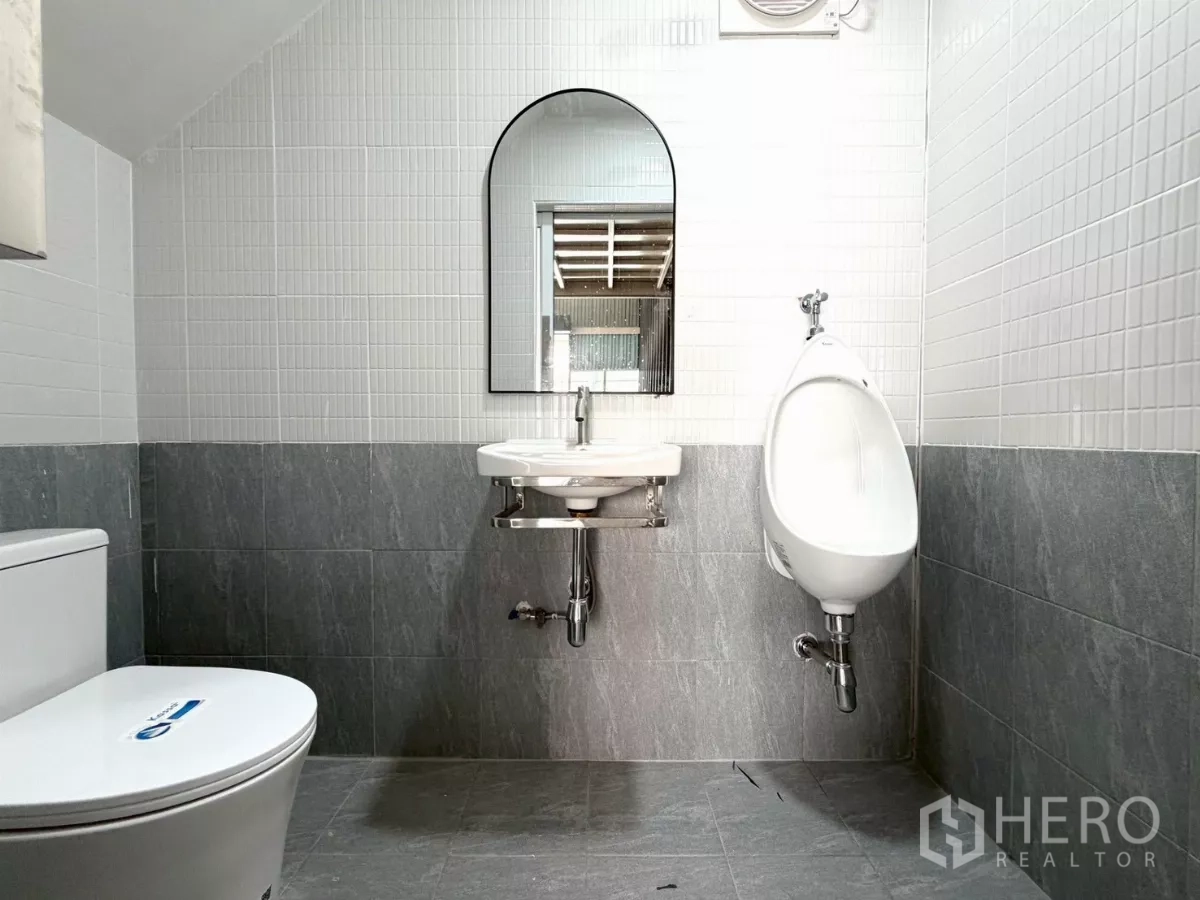 Warehouse for rent in Suan Luang, Bangkok - Clean tiled restroom inside the warehouse with toilet, urinal, sink and mirror.